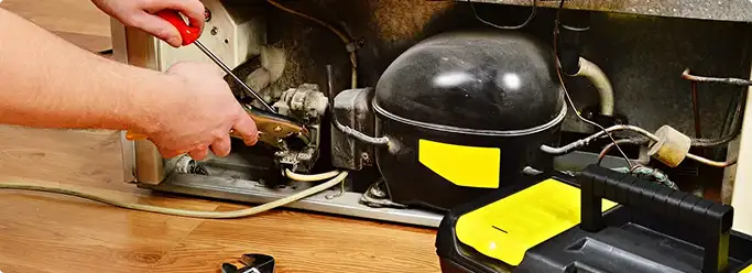 Refrigerator repair technician fixing the compressor and wiring in Dover Afb, DE