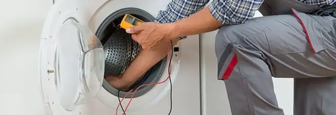 Dryer repair technician inspecting and repairing a clothes dryer in Dover, DE