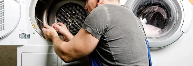 Dryer repair technician fixing a clothes dryer drum in Dover, DE