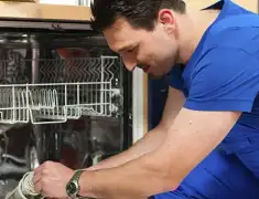 Dishwasher repair technician inspecting and servicing an open dishwasher in Dover, DE