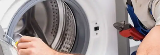 Appliance technician repairing a clothes dryer drum and internal parts in Dover, DE