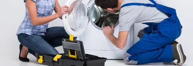 Washer repair technician inspecting a front-load washing machine with tools in Dover, DE