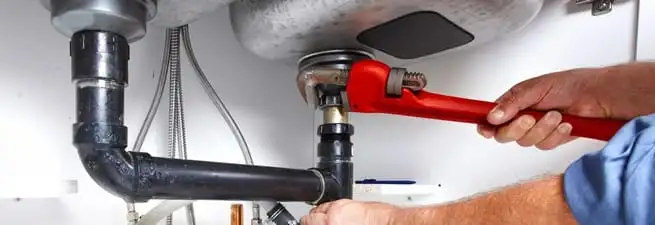 Garbage disposal repair technician tightening the sink drain and disposal connection in Dover, DE