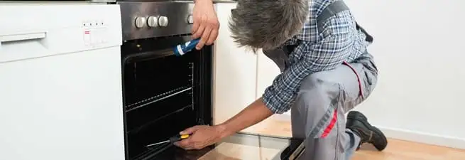 Oven repair technician inspecting and servicing an electric oven in Dover, DE