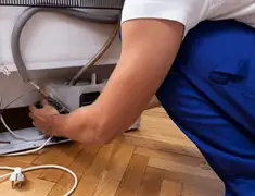 Appliance repair technician fixing refrigerator water line and connections in Dover, DE