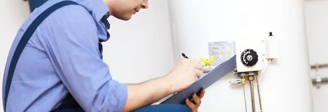 Water heater repair technician inspecting the unit and recording service notes in Dover, DE