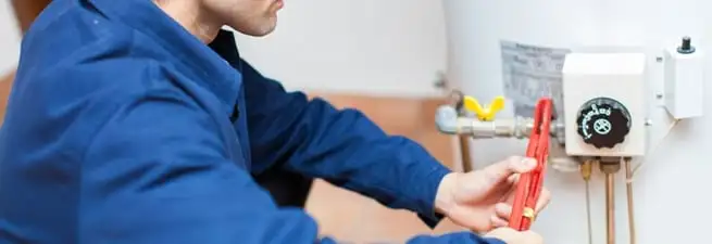 Water heater repair technician adjusting the temperature control and gas valve in Dover, DE